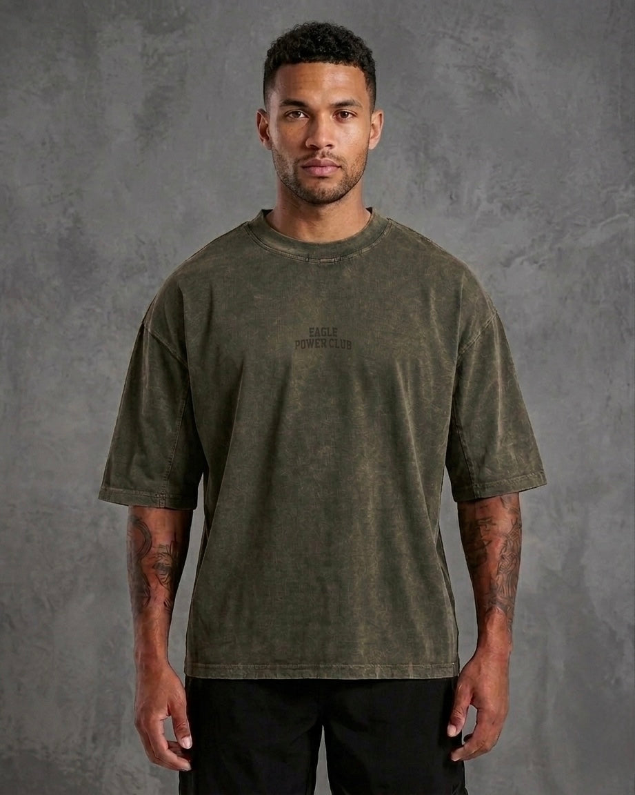 Man wearing a green t-shirt with text on a gray background