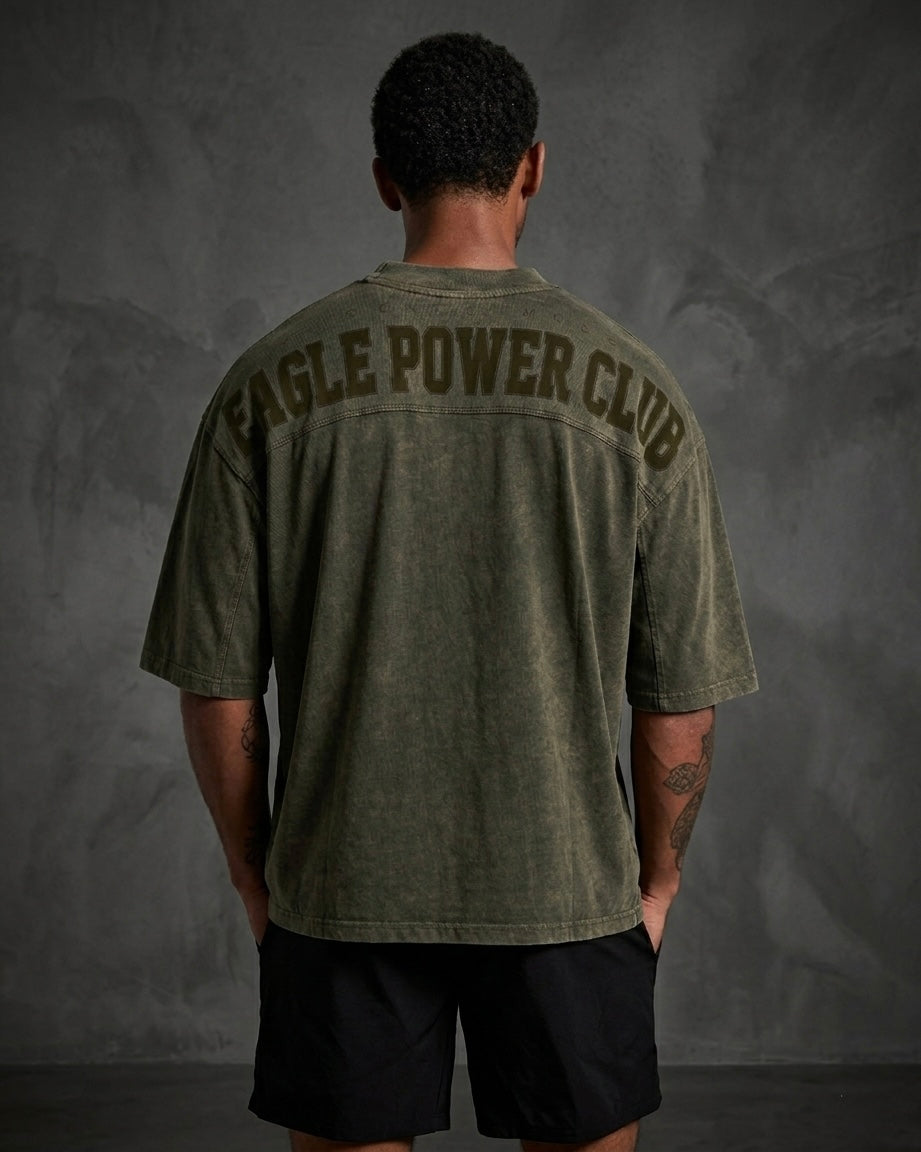 Person wearing a green t-shirt with 'Eagle Power Club' text on the back against a gray background