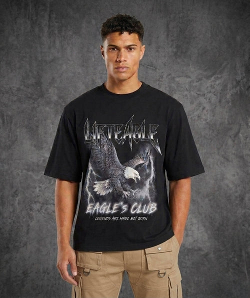 Person wearing a black t-shirt with an eagle design and text on a gray background